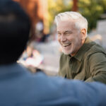 Two men talking and laughing outdoors while rebuilding trust after relapse